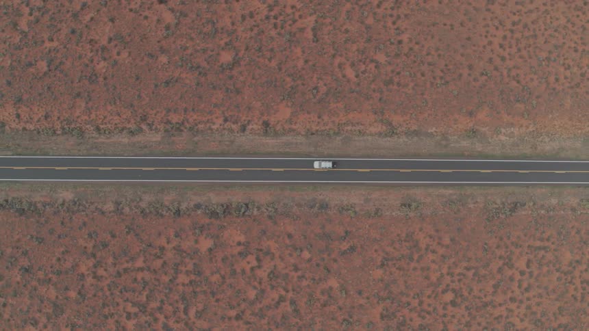 Lone white car driving on highway in the desert