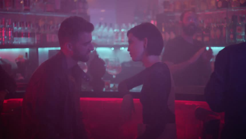A man is talking to a woman and kissing her in a bar