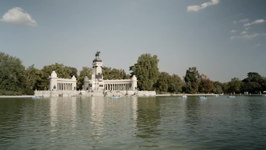 A group of people boating on a lake around a monument on the shore