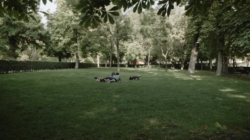 Two people are outside laying on the grass with their dog