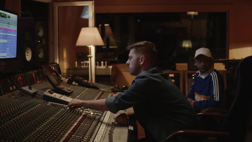 A man works at a soundboard in a recording studio
