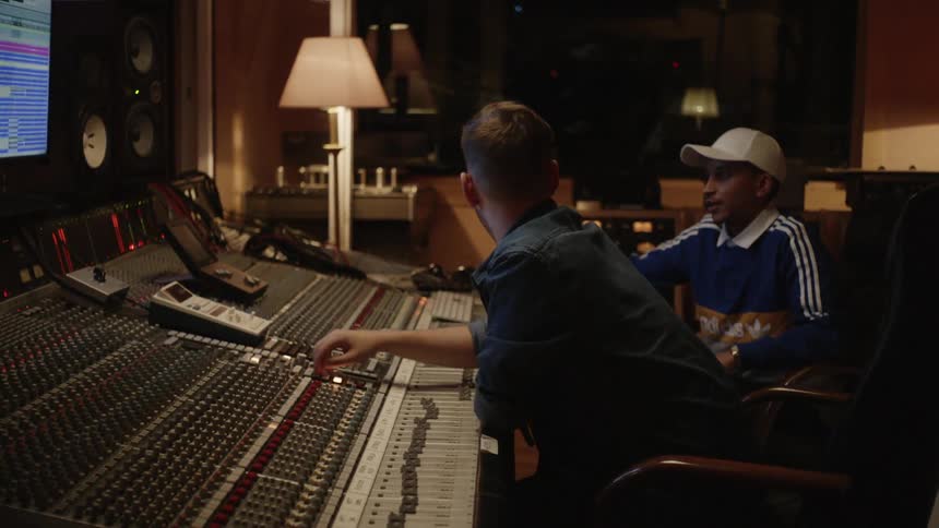 Two men in a music studio fiddling with many buttons