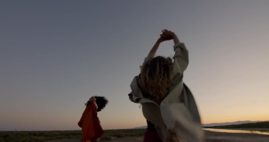 Three people walking and twirling along a beach