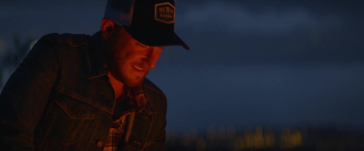 A man is talking outdoors at night by a fire