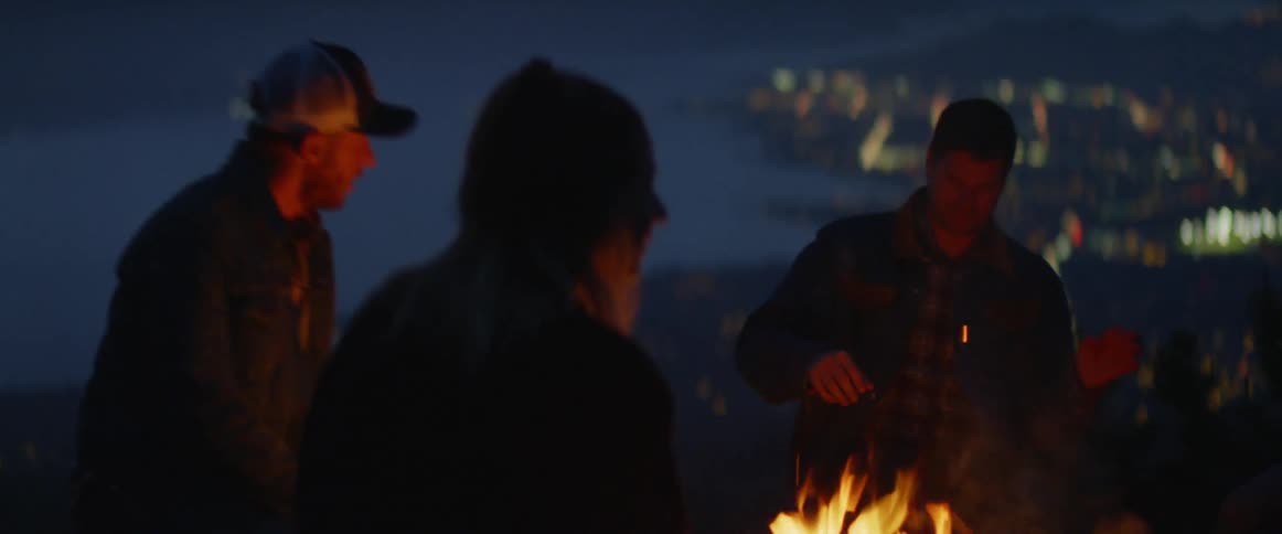 A group of people are by a fire outdoors