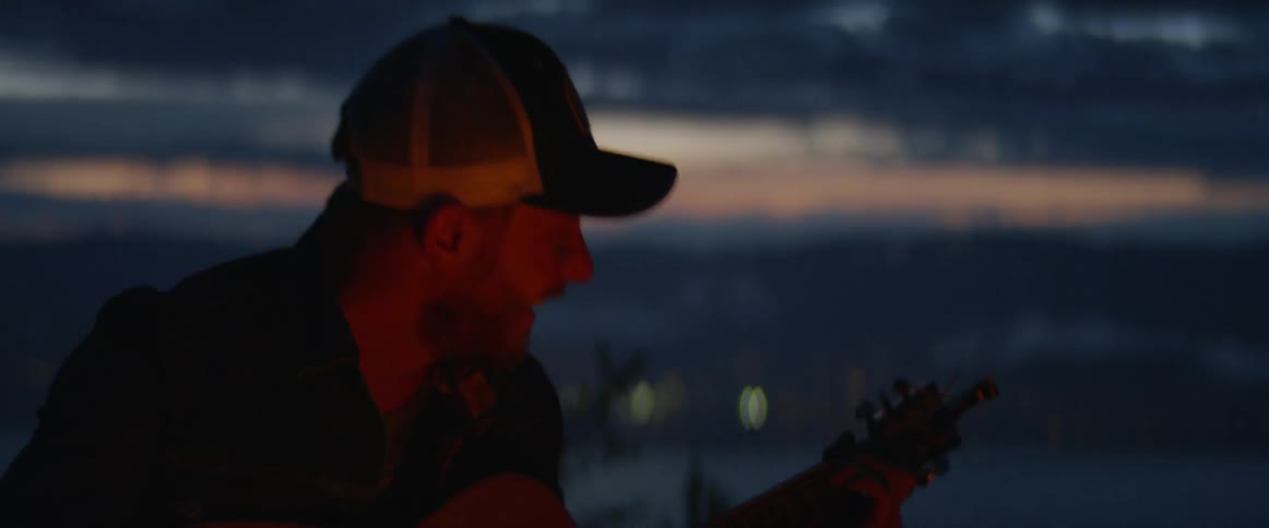 A man is playing guitar outdoors at night