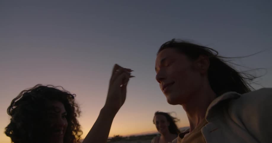A woman using tweezers on another woman's nose while a third watches and laughs