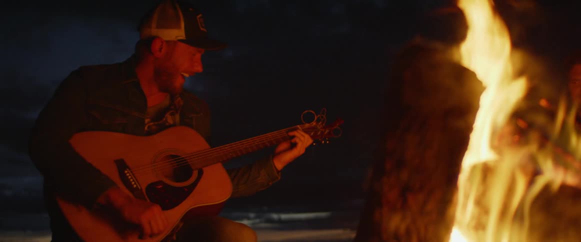 A man plays guitar by the campfire