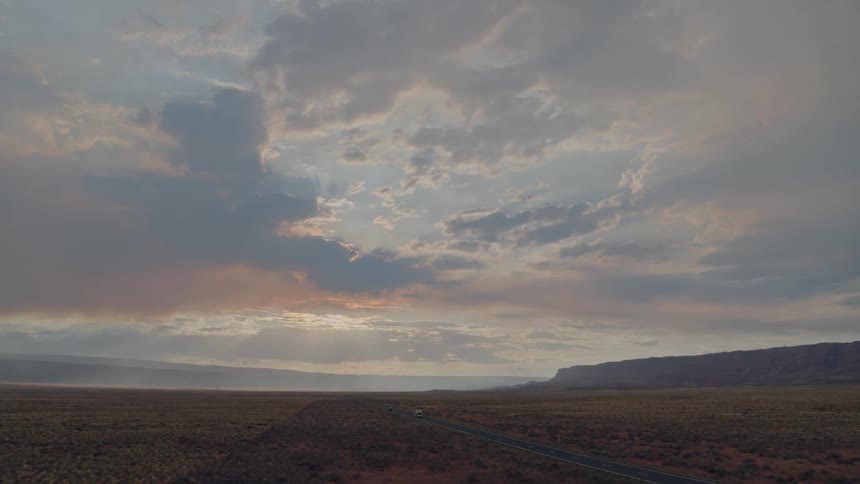 White motor home driving on highway at sunrise in desert