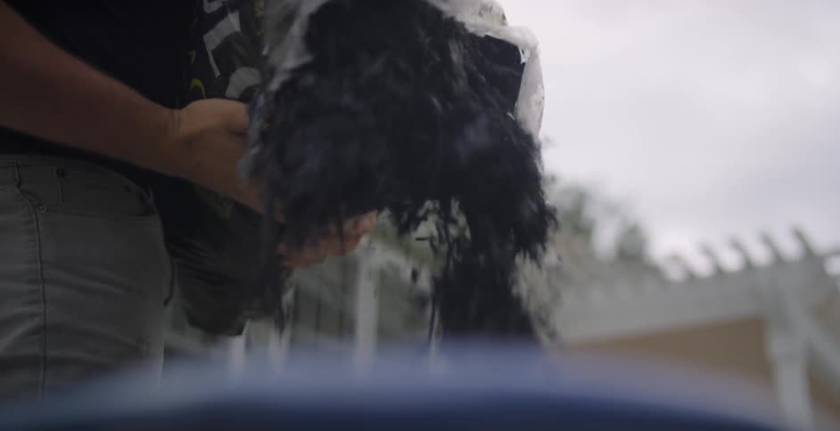 A man is putting dirt into a pot outdoors
