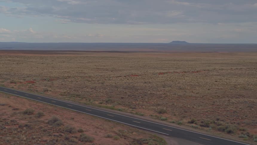 A clear road and green road sign passing through arid landscape