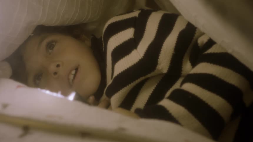 A child is laying under the blanket