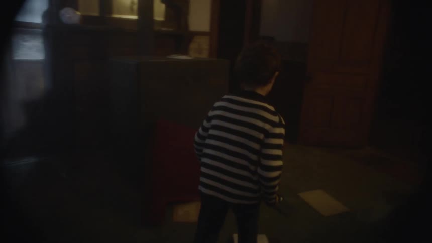 The child walks with a flashlight through the dark home