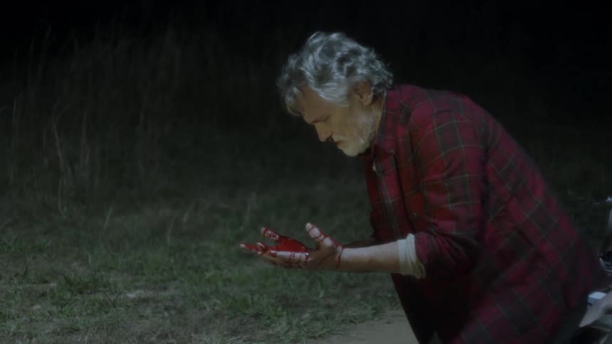 A man lifts his hands up covered with blood