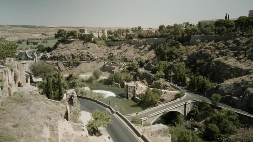 A small road runs around the hills by a bridge
