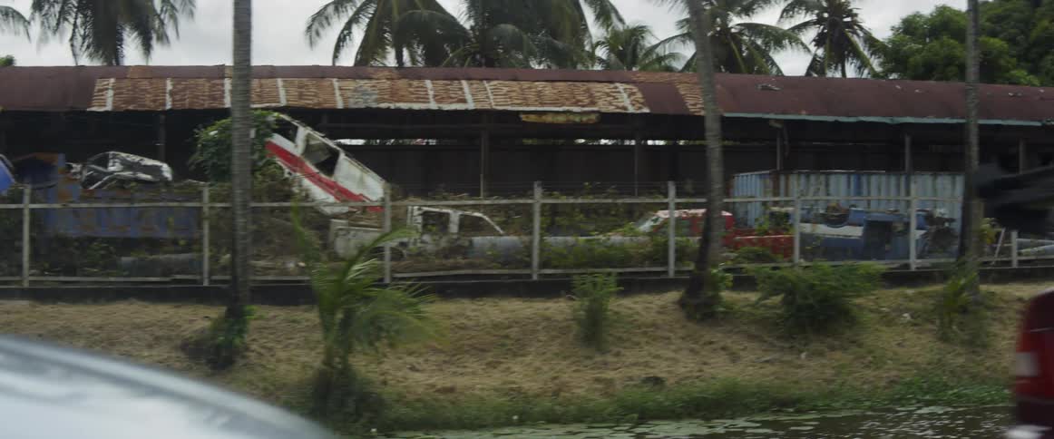 A building surrounded by abandoned vehicles being demolished