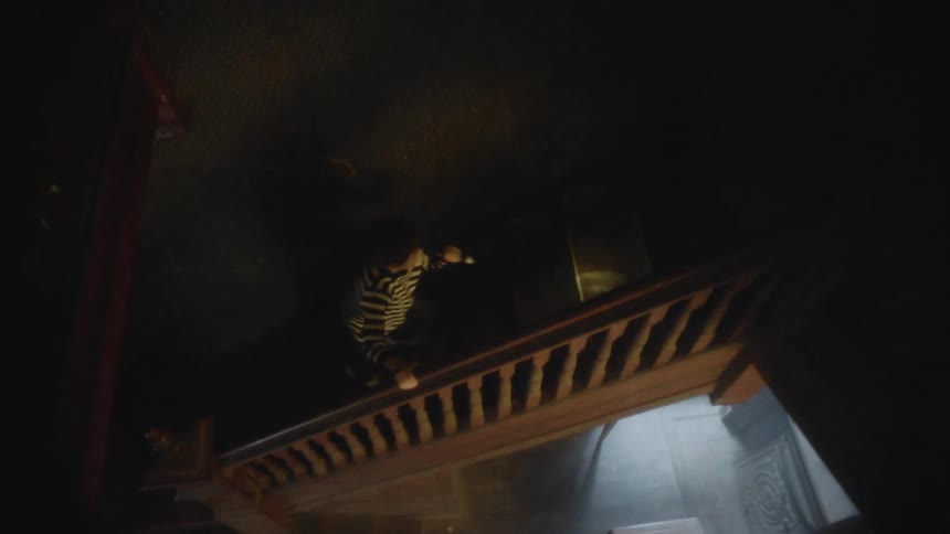 A man runs up the dark stairs in the home