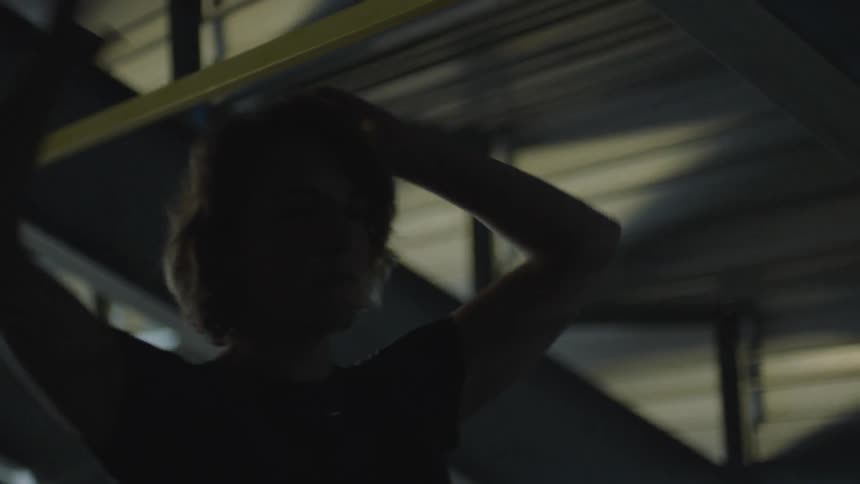A man rests his hands on his head as he walks and catches his breath