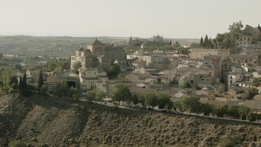 A village of white buildings surrounded by trees and hills