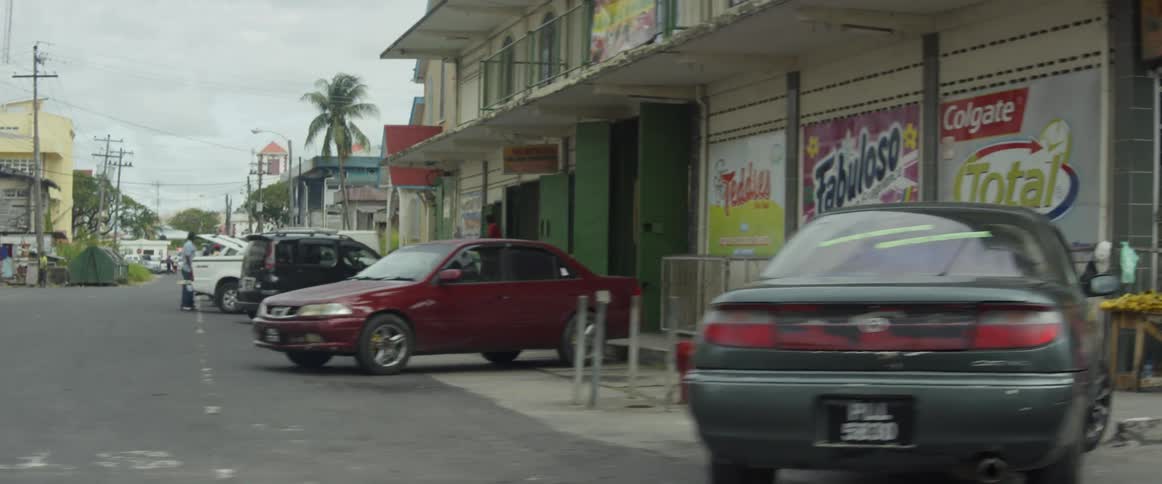 The people and vehicles are near the buildings