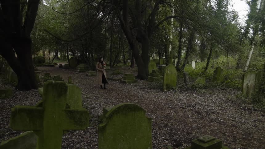 Woman slowly walks through a graveyard