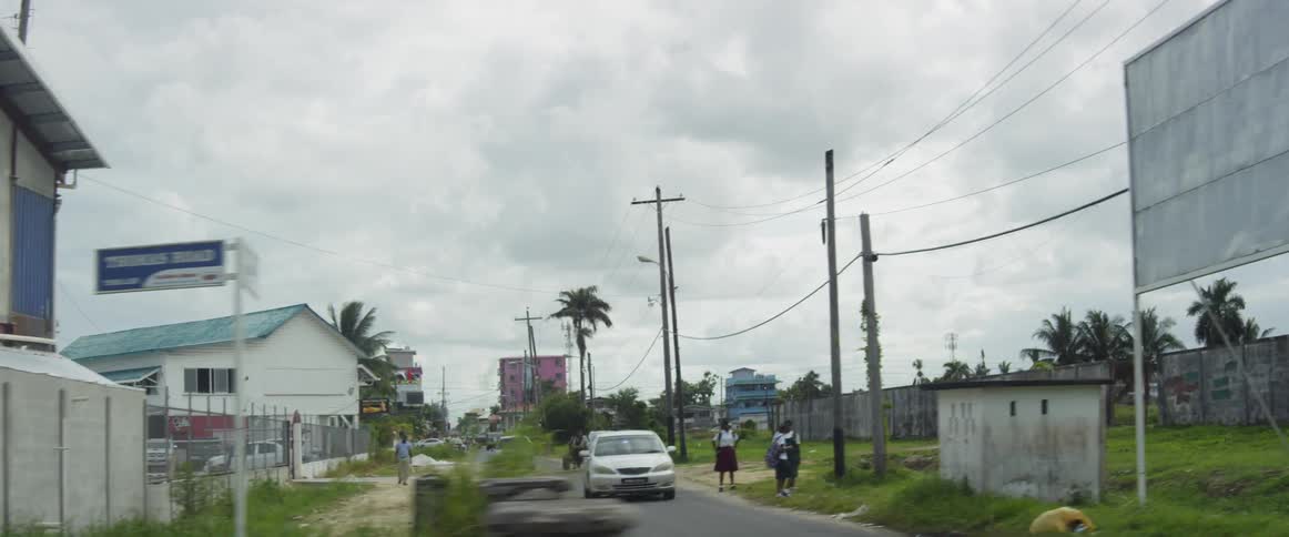 Cars driving and people walking down a street without sidewalks
