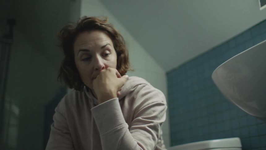 Woman looks pensively at something before combing hair back nervously