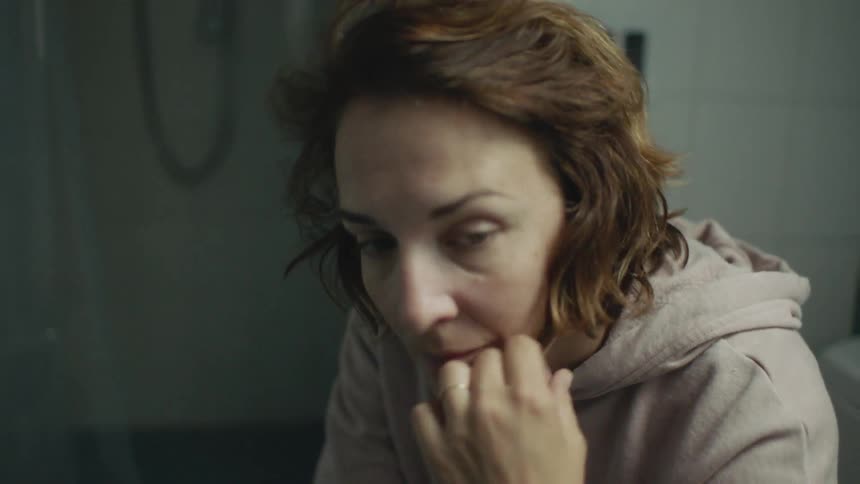 A woman leans forward in the room brushing her hair back