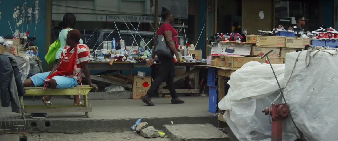 People walking down the street past tables full of items