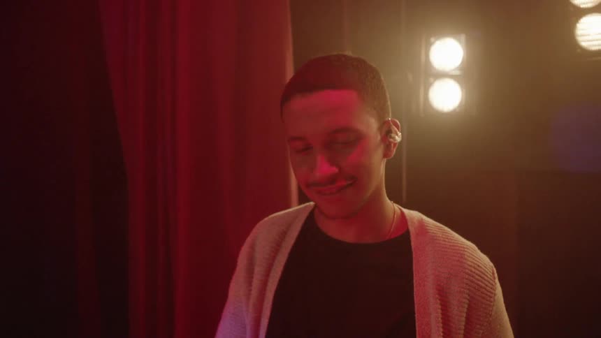 A man smiles as he plays the drums on stage