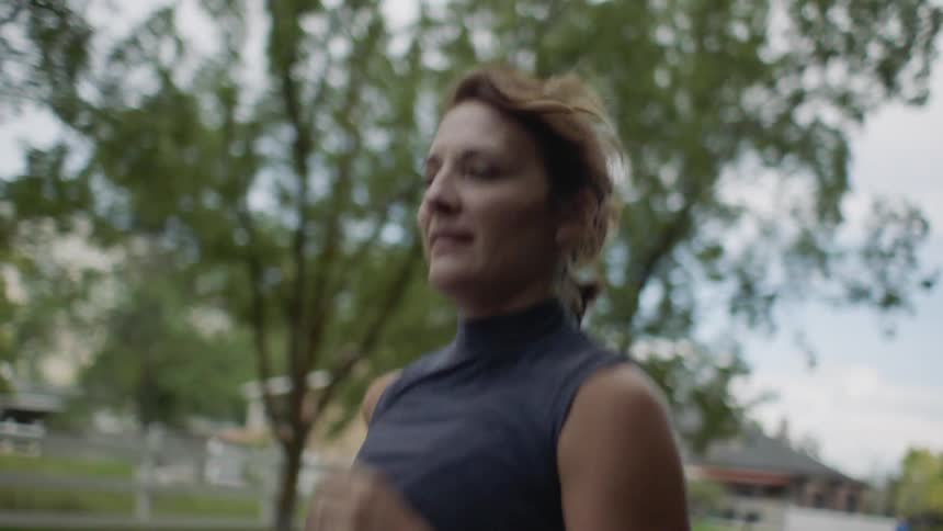 An adult woman jogging in a neighborhood on a cloudy day