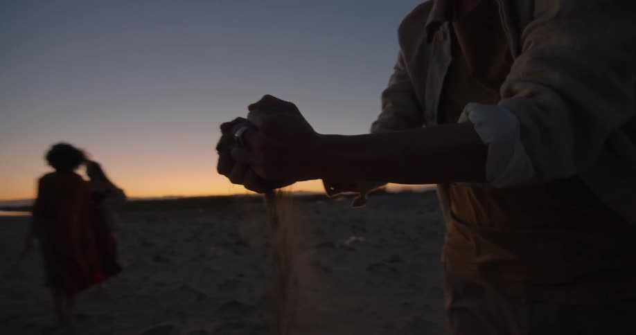 A woman holding sand while other people watch
