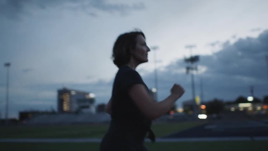 Woman fast walking on track at dusk