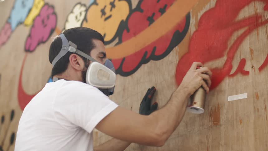 Spray painter paints the side of a wall