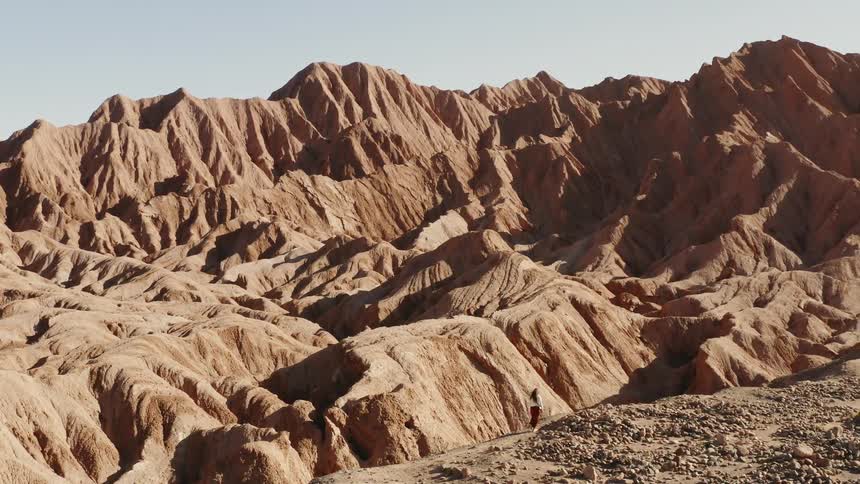 A woman walks along a path in a mountainous area