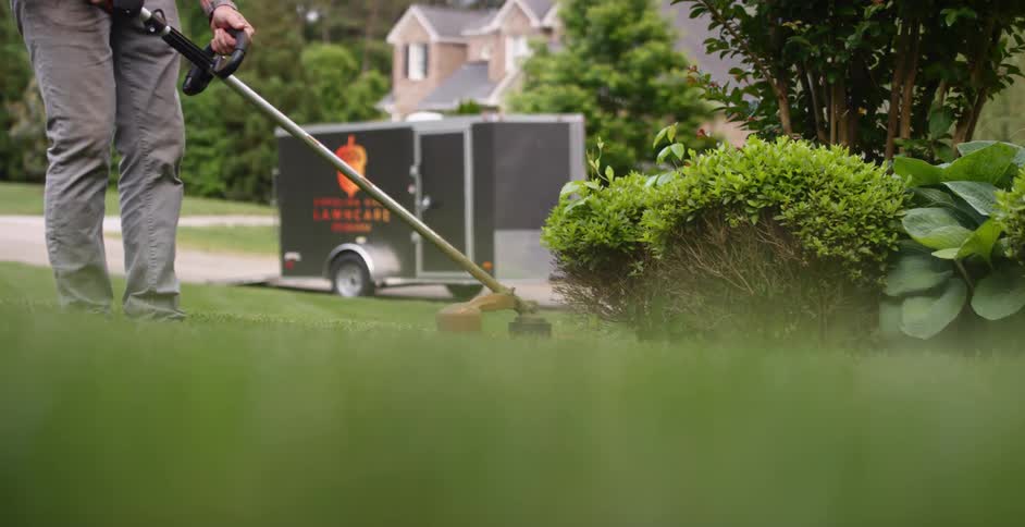 A landscaper weeding with tool