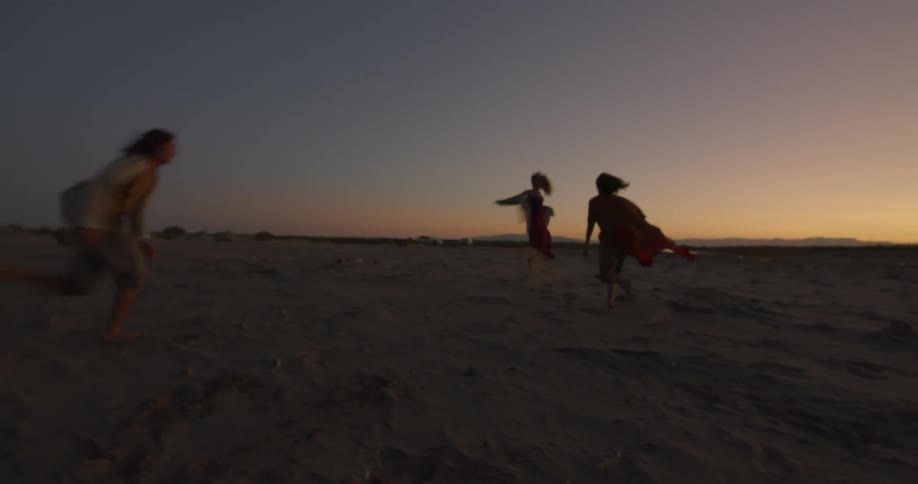 Three people dancing in the sand