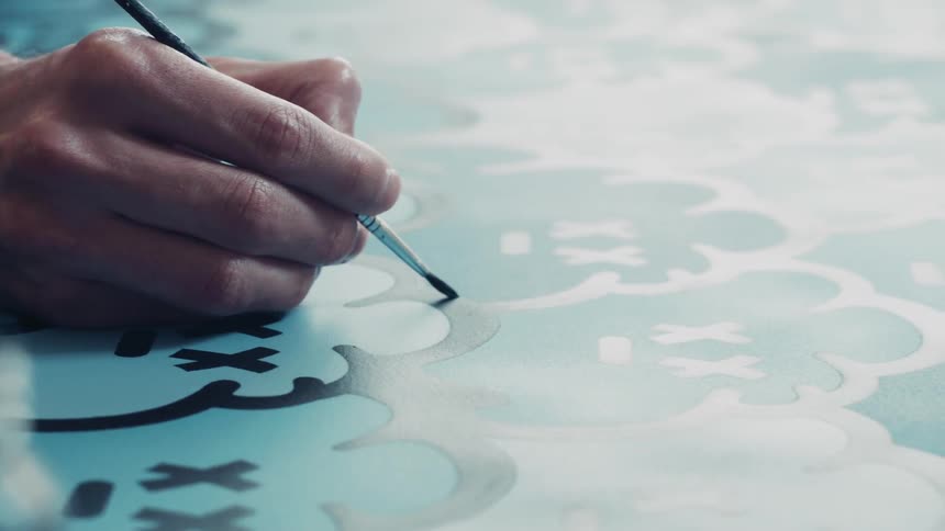 A man paints over a stencil with a paintbrush