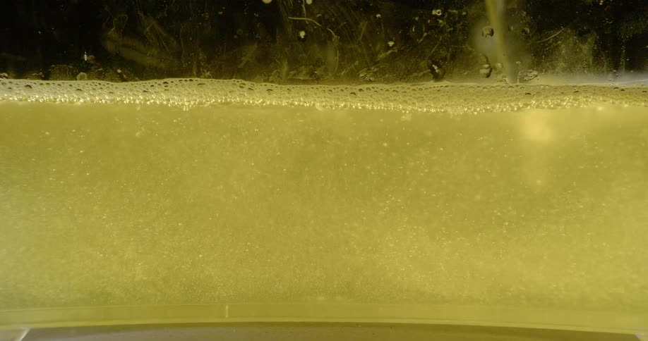 A knife blade is moved through liquid in a clear container then lifted out