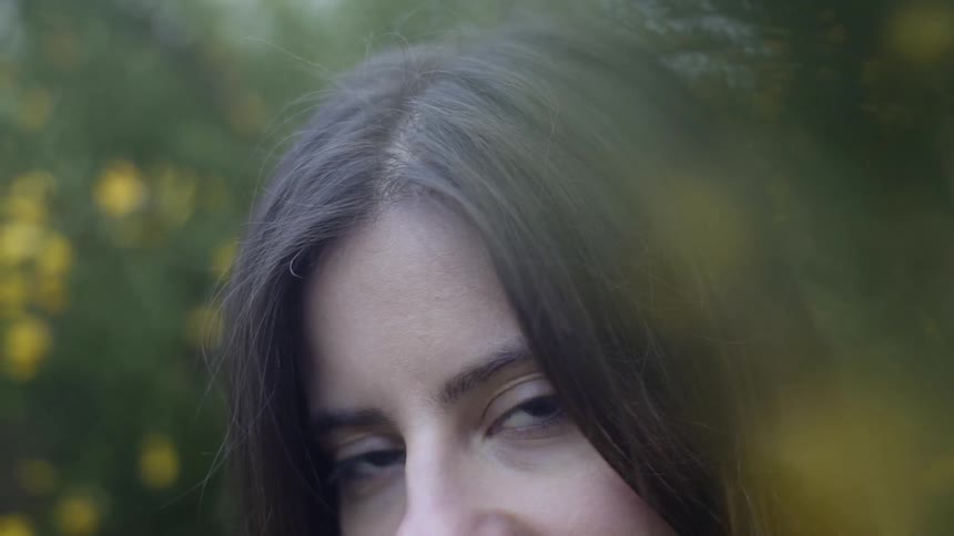 A woman looks up while standing near trees