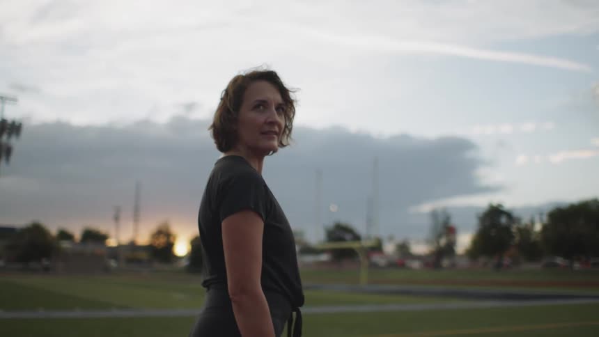 A woman on a field track looking behind her