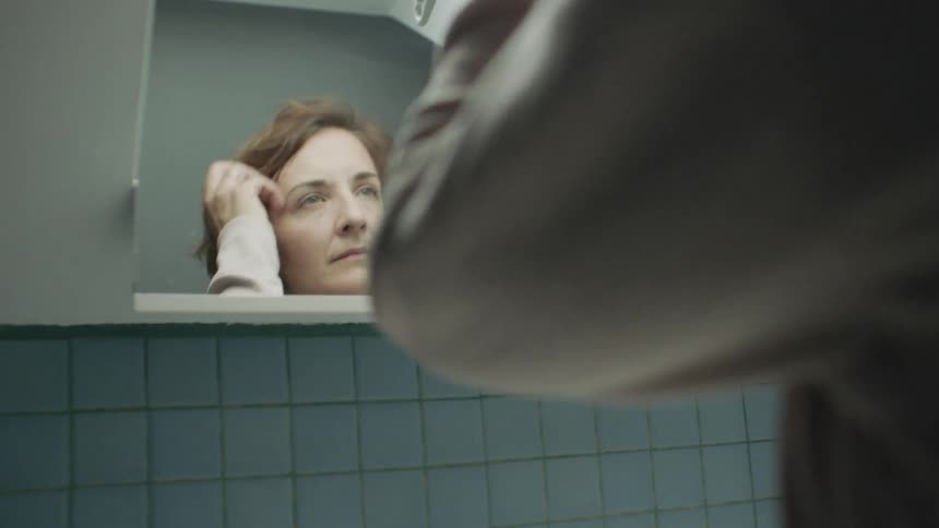 Woman looks at self in bathroom mirror