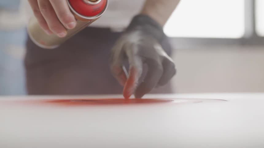 A person is using spray paint and wearing a glove