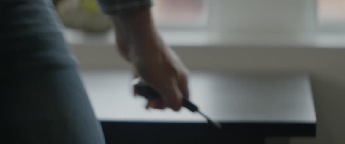 A person picks up a set of keys from a dark wooden table