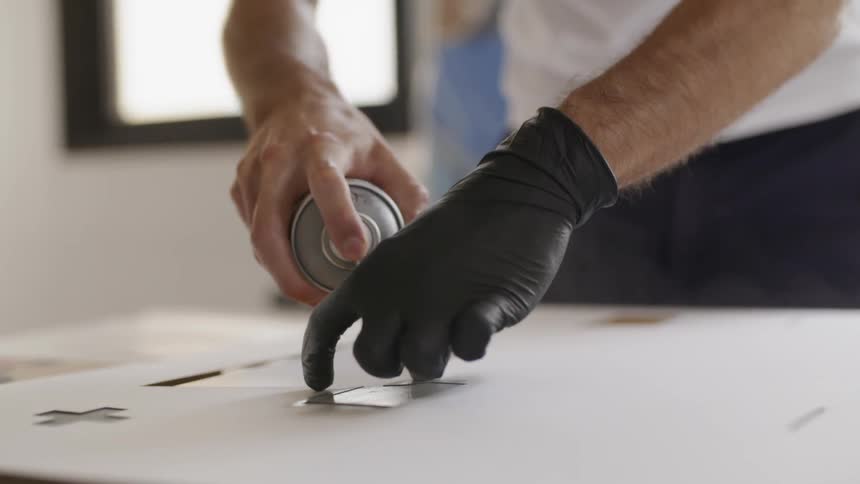 A man wearing one glove is using spray paint