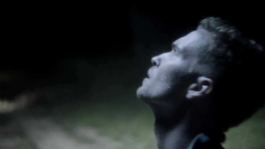 Man looks up sky at night with car headlights on