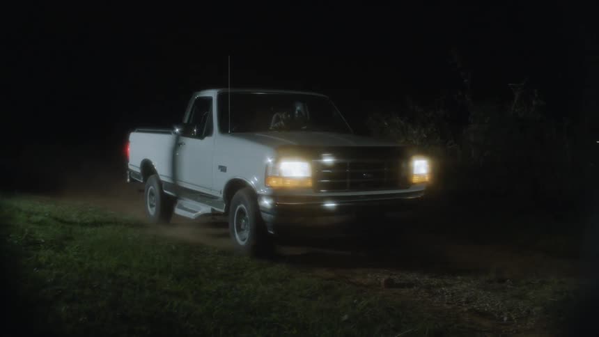 White truck sliding to a stop and turning off its headlines on a dirt road