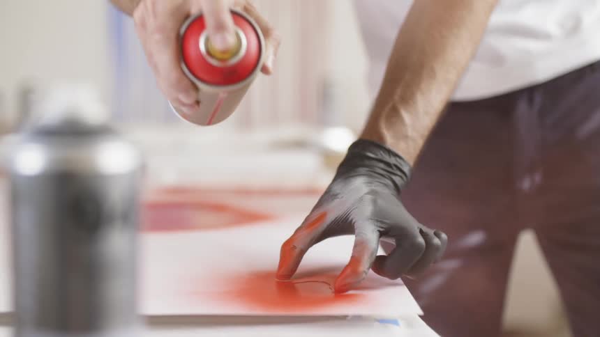 A man is spray painting in the room