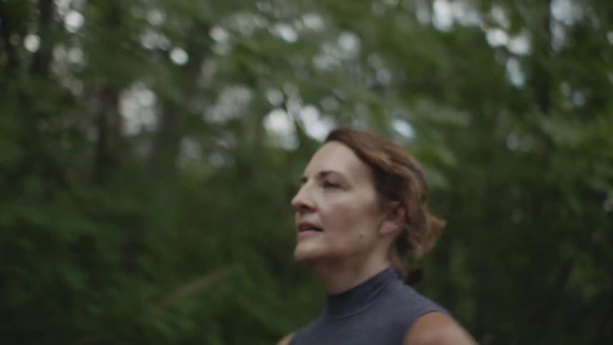 A woman jogging next to a forest
