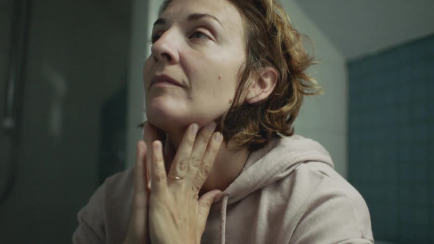A woman wipes her face in the bathroom